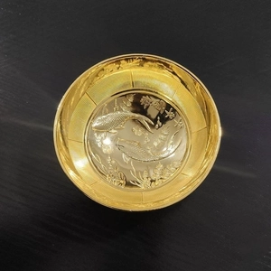 Makro-Detail einer goldenen Minischale mit Koi-Relief und glücksbringenden Zeichen