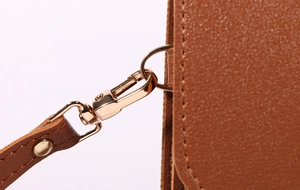 Macro shot of brown pebble leather shoulder strap with golden metal lobster clasp and D-ring