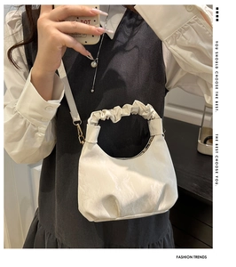 Detail of white hobo bag with pleated handle and cloud texture worn by a model