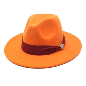 Close-up of orange wool fedora with burgundy ribbon and silver rhinestone buckle