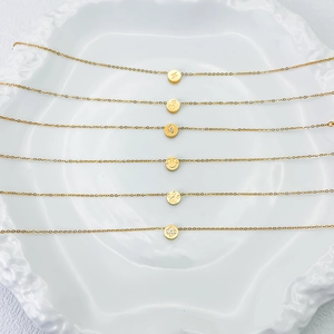 Detalle de seis collares de acero de titanio dorado con varios colgantes circulares