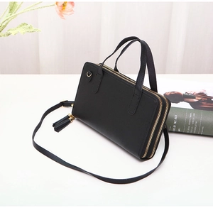 Close-up of black double-layered crossbody bag with tassel and gold hardware