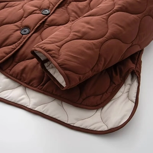 Détails de la veste matelassée en coton bronze avec doublure beige contrastée