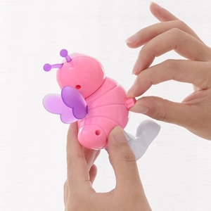 Pink bee clockwork toy made of plastic being wound up by hand on a white background