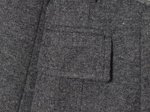 Gros plan détaillé sur la texture du tweed gris foncé et les coutures de la poche du costume