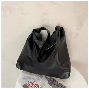 Detailed view of a black large capacity tote bag with soft leather texture on a white table