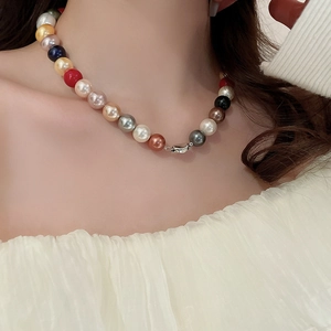 Close-up of colorful pearl necklace with mixed white, gold, and blue beads on a model