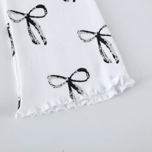 Pantalon évasé en maille côtelée blanche avec motifs nœuds noirs et ourlet festonné