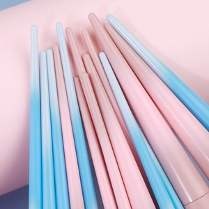 Gros plan des manches de pinceaux de maquillage avec dégradé rose bleu et fini mat