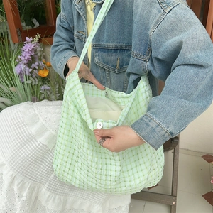 Détail du sac cabas à carreaux vert clair avec bouton pression porté à l'épaule