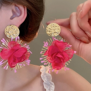 Close-up of pink fabric flower earrings with hammered gold metal details on a model