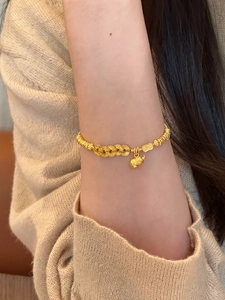 Detailed view of gold calabash bracelet with pig charm and coin-shaped links on wrist