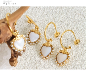 Detail of gold-plated heart earrings with mother of pearl inlay and rose accents