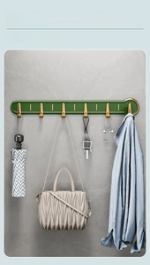Detail of luxury green wall hooks with gold accents for keys and bags in bathroom