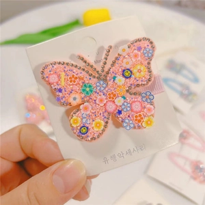 Close-up of pink butterfly hair clip with rhinestones and colorful floral patterns
