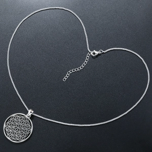 Macro shot of silver Tree of Life hollow pendant with geometric round flower pattern