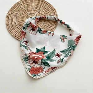 Detail of floral headscarf with lace edges and elastic band on a woven mat