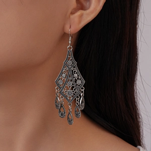 Detail view of vintage silver hollow flower earrings with teardrop fringe on model