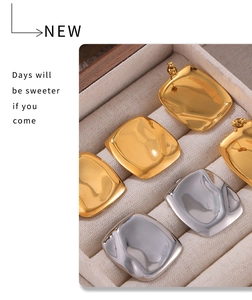 Detailed macro of irregular textured gold and silver square stud earrings in a luxury box