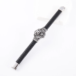 Close-up of a men's black braided leather bracelet featuring a silver metal lion head charm