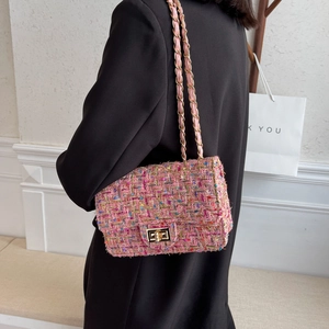 Pink tweed crossbody bag with gold chain strap worn over a black wool coat