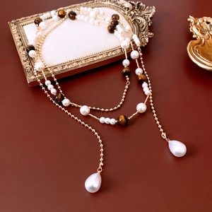 Detailed view of vintage pearl and tiger eye stone necklace with drop pendants