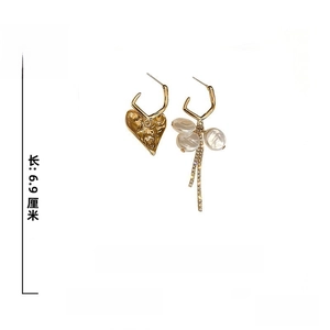 Détail de boucles d'oreilles cœur asymétriques avec perles, strass et aiguilles en argent 925