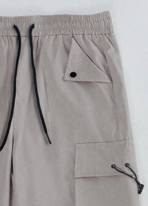 Detail view of elastic waistband with black drawstrings and metal eyelets on cargo pants