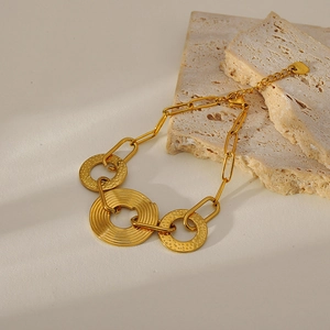 Detailed close-up of golden stainless steel chain bracelet with textured round charms