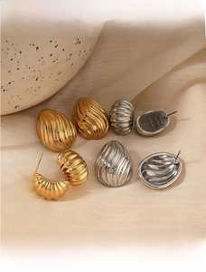 Close-up of gold and silver waterdrop earrings with elegant ribbed texture details