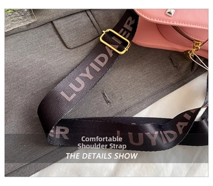 Pink leather guitar bag with branded black woven strap and heart-shaped zipper