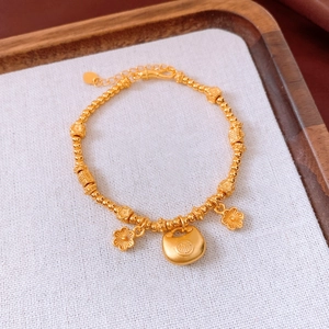 Macro view of 24K gold plated beaded bracelet featuring Ruyi lock and plum blossom charms