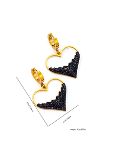 Dettaglio di orecchini a cuore in oro con pavé di zirconi neri e design asimmetrico