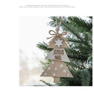 Close-up of wooden Christmas tree hanging ornament with Joyeux Noel text on tree branch