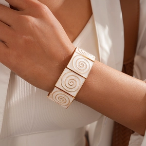 Detail view of a vintage gold bracelet with white enamel squares and spiral textures