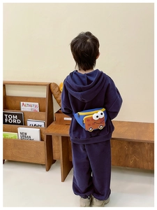 Rear view of a child wearing a blue cartoon bus crossbody bag with plaid details