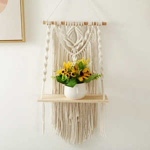 Detail of bohemian hand-woven cotton macrame wall shelf with a sturdy wooden plank