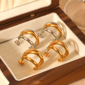 Three-layer mixed gold and silver stainless steel earrings on a premium jewelry box pad