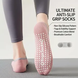 Rosa Yoga-Socken mit weißen Silikon-Noppen auf einer grauen Matte, rutschfest