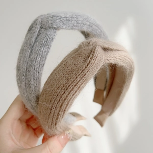 Detail shot of the knitted texture and knot design on beige and grey winter headbands