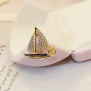 Elegant gold sailboat brooch with crystal inlay presented in a pink jewelry box
