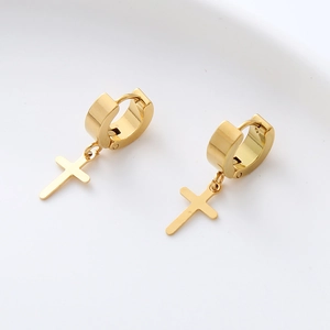 Macro shot of gold-plated stainless steel hoop earrings with cross pendant on white tray