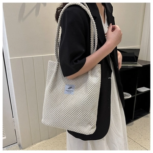 Shoulder shot of a beige corduroy tote bag featuring a small You need this one fabric label