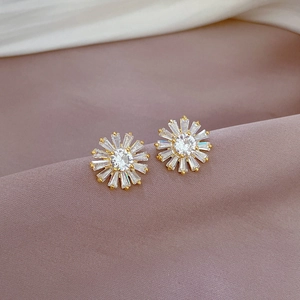 Detailed macro shot of sunflower stud earrings with zircon inlay on purple silk fabric