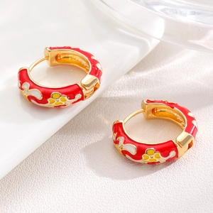 Macro detail of red enamel floral hoop earrings with gold finish and vintage patterns