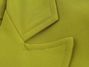 Macro shot of lime green blazer fabric with precise stitching and high-quality textile texture