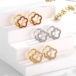 Macro shot of three flower-shaped earrings in gold and silver with sparkling crystals