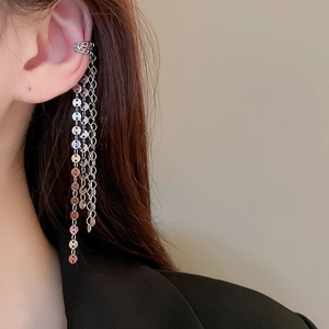 Detail of silver tassel ear cuff featuring layered chain and metallic sequins on ear