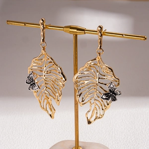 Detailed macro view of gold hollow leaf earrings featuring 3D butterfly ornaments