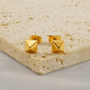Vue macro de boucles d'oreilles pyramides géométriques en acier doré 18 carats